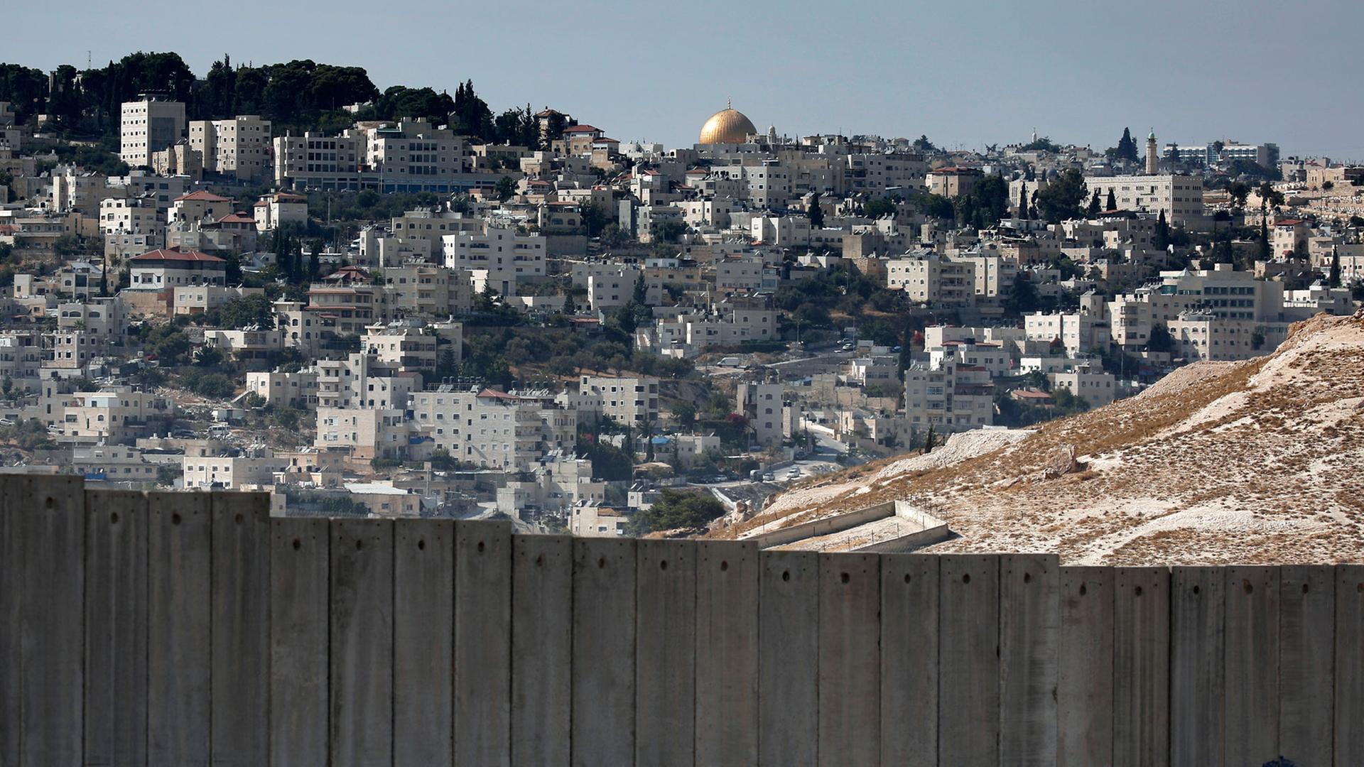 Einer Mauer trennt Jerusalem in einen israelischen und palästinensischen Teil, im Hintergrund der Felsendom mit der goldenen Kuppel.