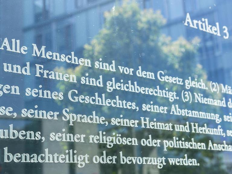 Der Wortlaut des Artikels 3 des deutschen Grundgesetzes auf einer Glaswand. Eine Installation von Dani Karavan.