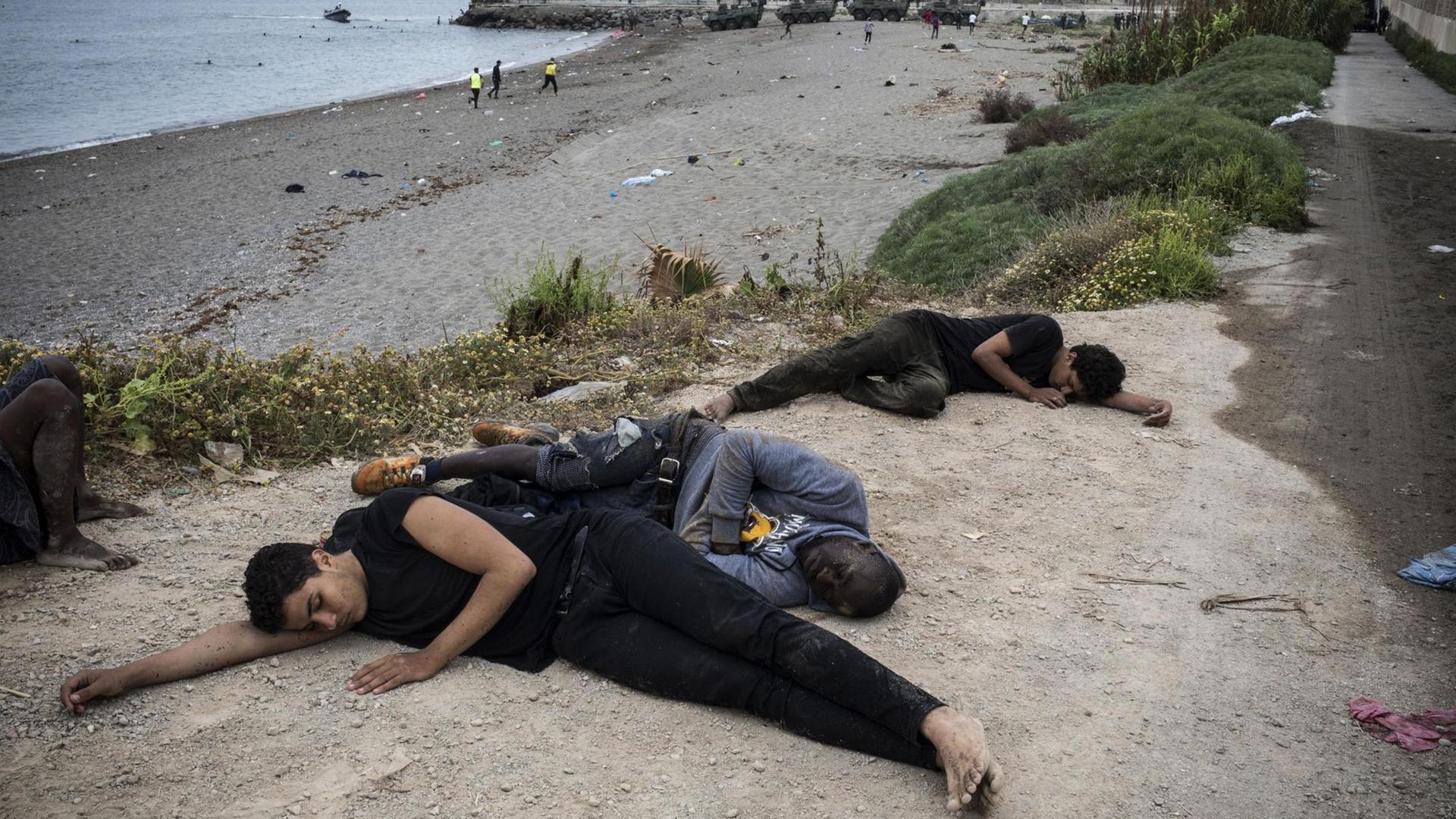 Menschen liegen erschöpft am Strand Menschen liegen erschöpft am Strand