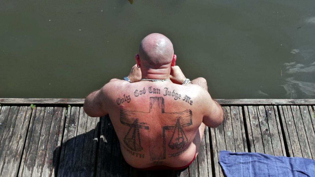 Ein Badegast in Hamburg mit einem Tattoo mit einer religiösen Aufschrift und Symbolik Ein Badegast in Hamburg mit einem Tattoo mit einer religiösen Aufschrift und Symbolik