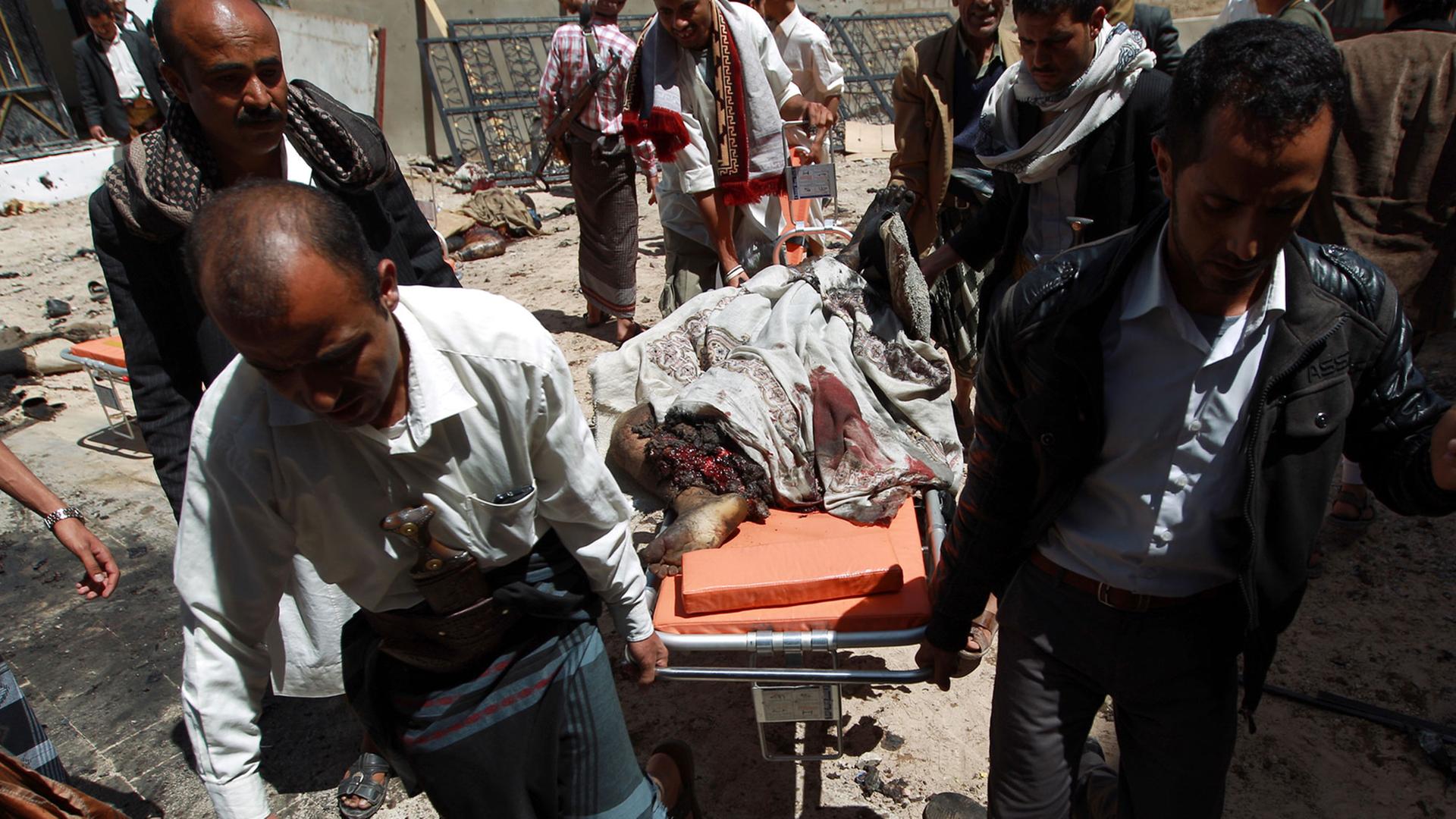 Jemenitische Sicherheitskräfte und Mitglieder der schiitischen Huthi-Miliz tragen eine Leiche nach einem Bombenanschlag auf die Badr-Moschee im Süden der Stadt Sanaa. Jemenitische Sicherheitskräfte und Mitglieder der schiitischen Huthi-Miliz tragen eine Leiche nach einem Bombenanschlag auf die Badr-Moschee im Süden der Stadt Sanaa.