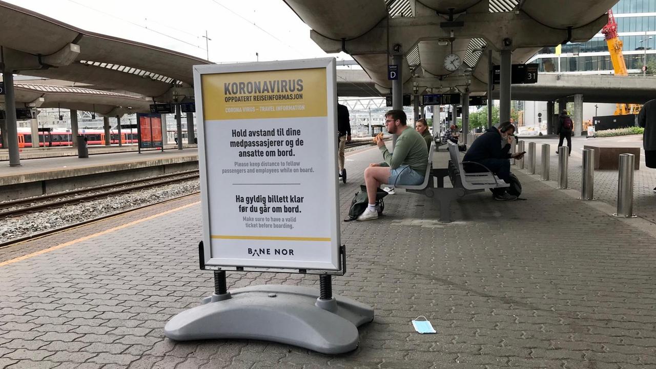 Neben den Bahnhofsgleisen steht am Bahnsteig ein großes gerahmtes Plakat mit Warnhinweisen. Neben den Bahnhofsgleisen steht am Bahnsteig ein großes gerahmtes Plakat mit Warnhinweisen.
