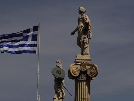 Die griechische Flagge weht neben den Statuen von Athene und Apollo vor der Akademie von Athen