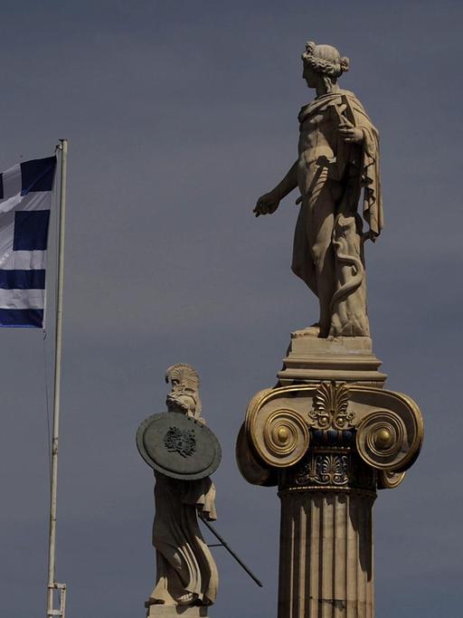 Die griechische Flagge weht neben den Statuen von Athene und Apollo vor der Akademie von Athen
