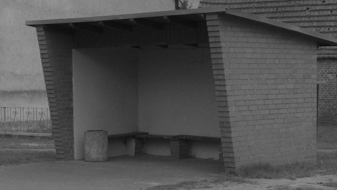 Ein schwarz-weiß Bild einer leeren Bushaltestelle.