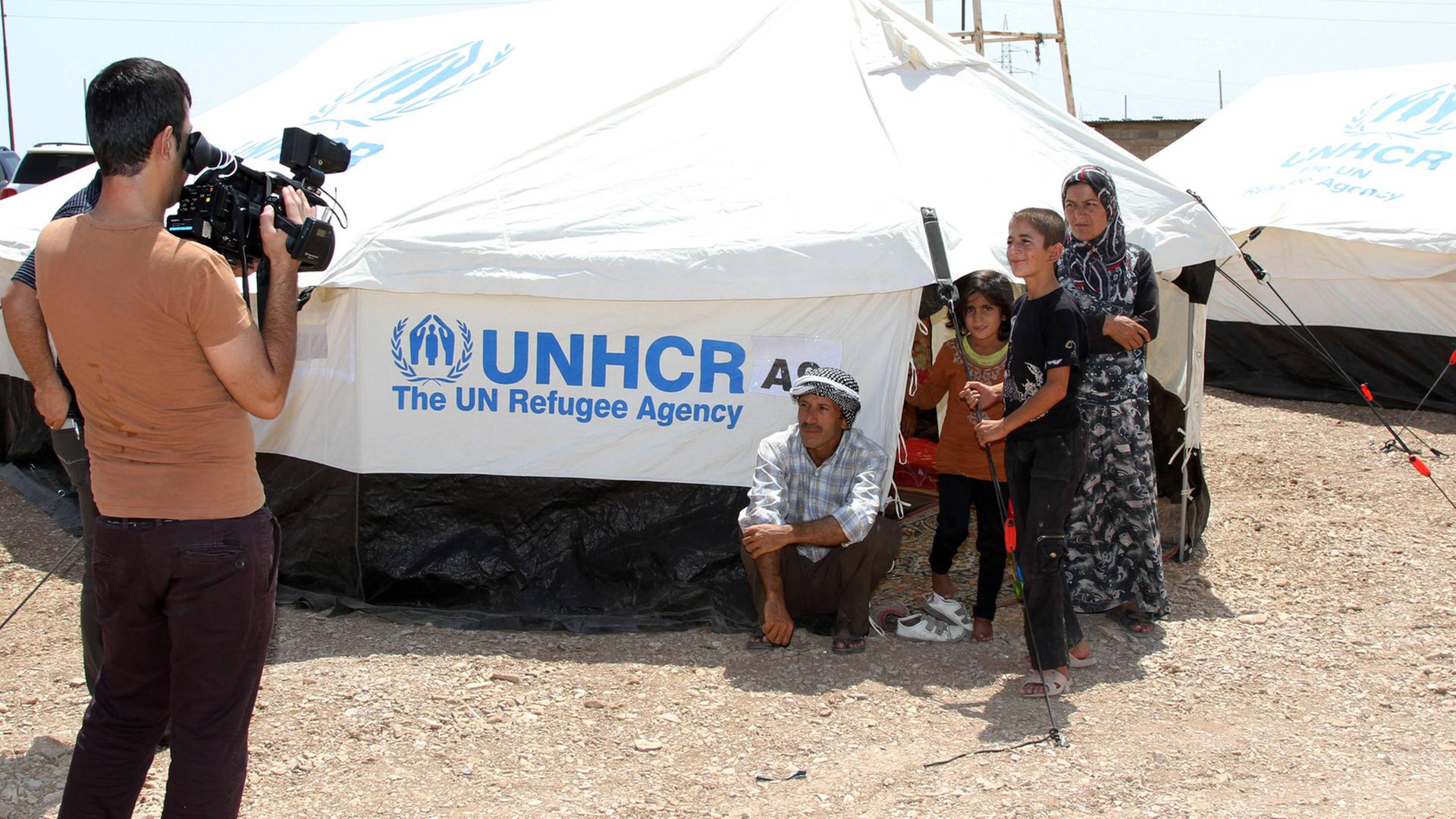 Ein Kameramann filmt eine Flüchtlingsfamilie an einem UNHCR-Zelt Ein Kameramann filmt eine Flüchtlingsfamilie an einem UNHCR-Zelt