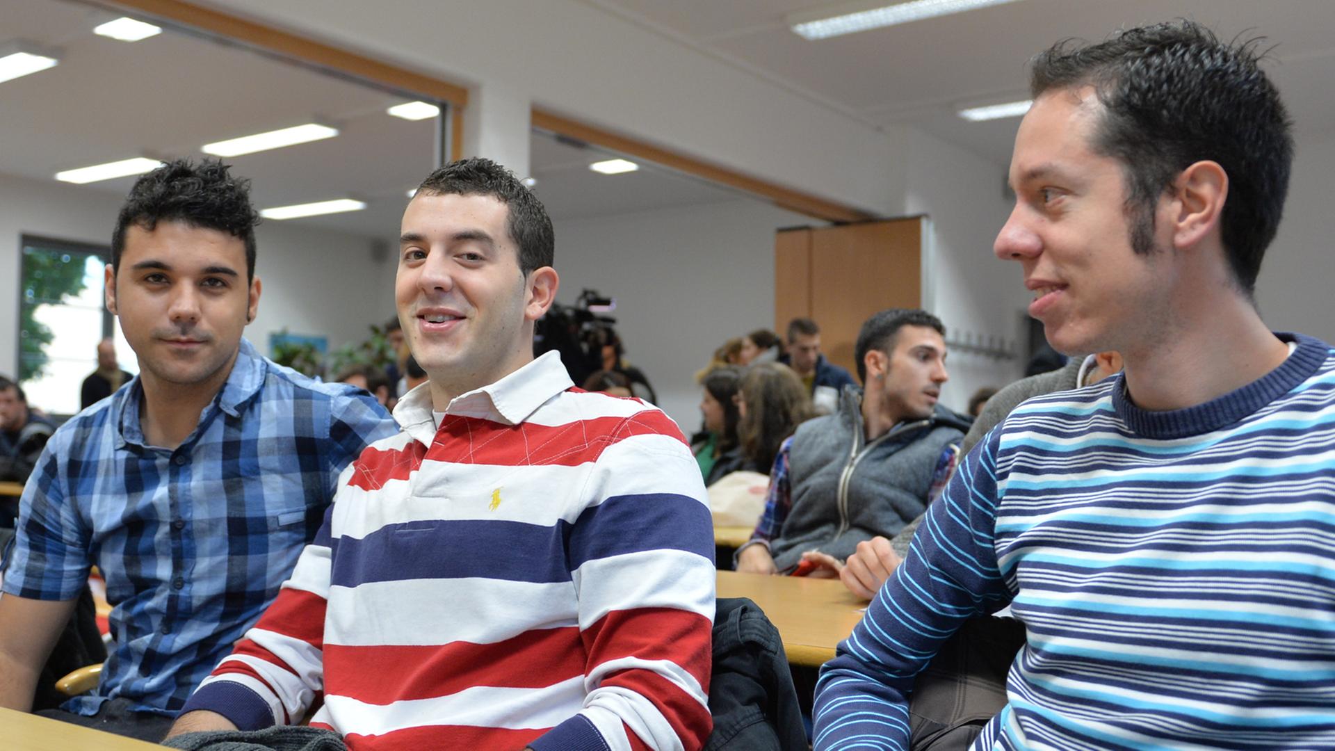 Drei junge Spanier sitzen in einem Konferenzraum an einem Tisch Drei junge Spanier sitzen in einem Konferenzraum an einem Tisch