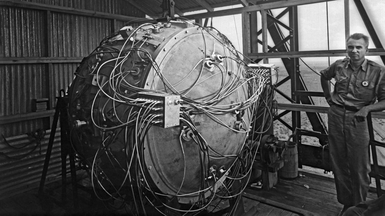 Die "Trinity"-Testbombe mit dem Spitznamen "The Gadget" hängt noch nicht vollständig aufgebaut im Test-Turm, daneben der US-Physiker Norris Bradbury (Juli 1945) Die "Trinity"-Testbombe mit dem Spitznamen "The Gadget" hängt noch nicht vollständig aufgebaut im Test-Turm, daneben der US-Physiker Norris Bradbury (Juli 1945)