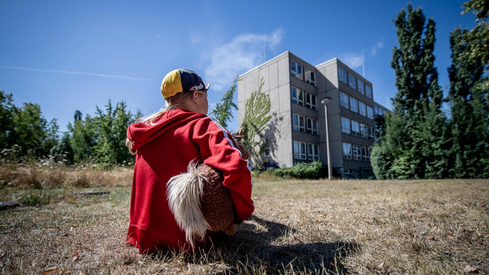 31. Juli 2020: Leipzig (Sachsen), Stadtteil Gruenau: Ein Kind sitzt vor einem Plattenbau in Leipzig-Gruenau. Foto: Thomas Eisenhuth | Verwendung weltweit 31. Juli 2020: Leipzig (Sachsen), Stadtteil Gruenau: Ein Kind sitzt vor einem Plattenbau in Leipzig-Gruenau. Foto: Thomas Eisenhuth | Verwendung weltweit