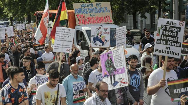 Das Bild zeigt Teilnehmer einer antiisraelischen Demonstration anlässlich des jährlich stattfindenden Al-Kuds-Tag in Berlin. Sie halten zahlreiche israelkritische Spruchbänder und Schilder hoch.