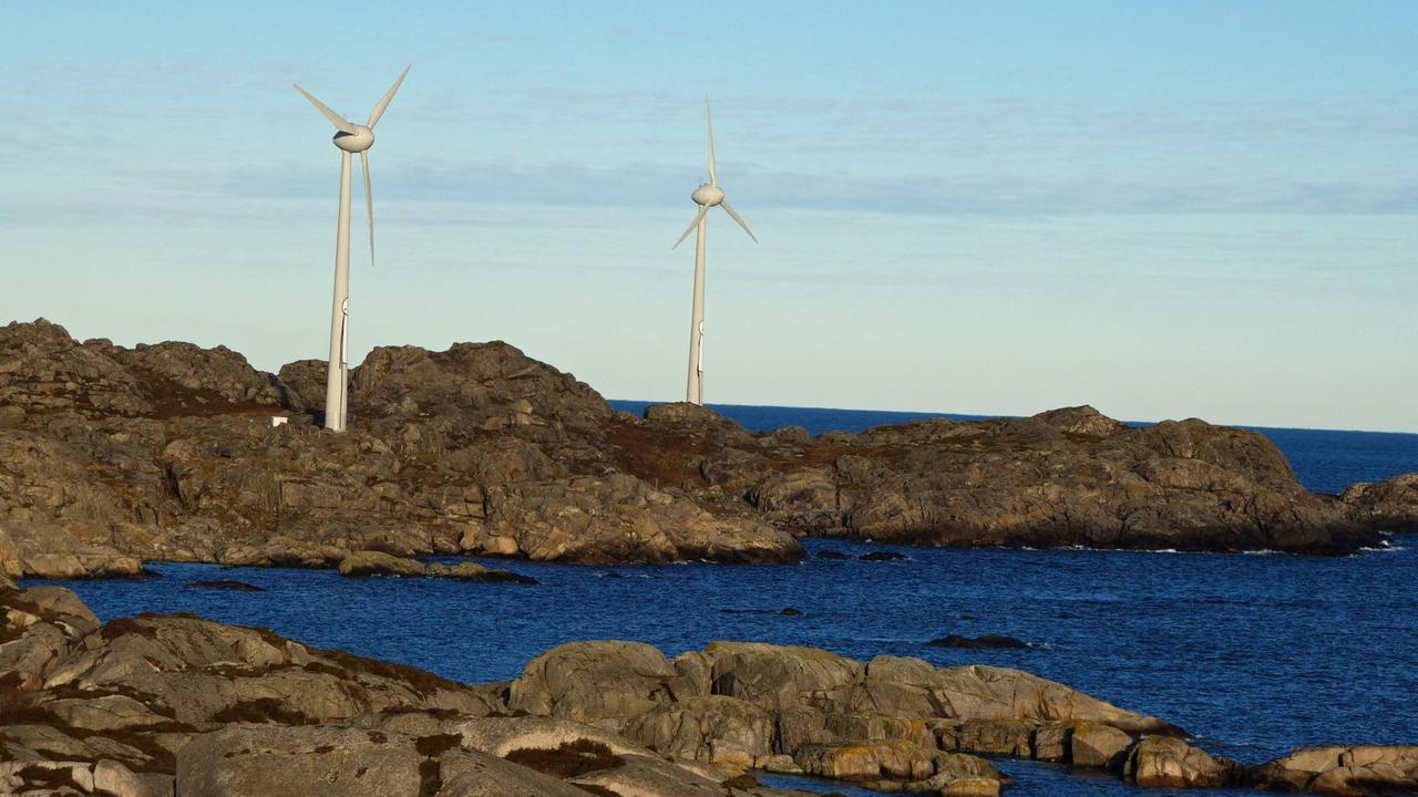 Zwei Windräder am felsigen Ufer dicht am Meer. Zwei Windräder am felsigen Ufer dicht am Meer.