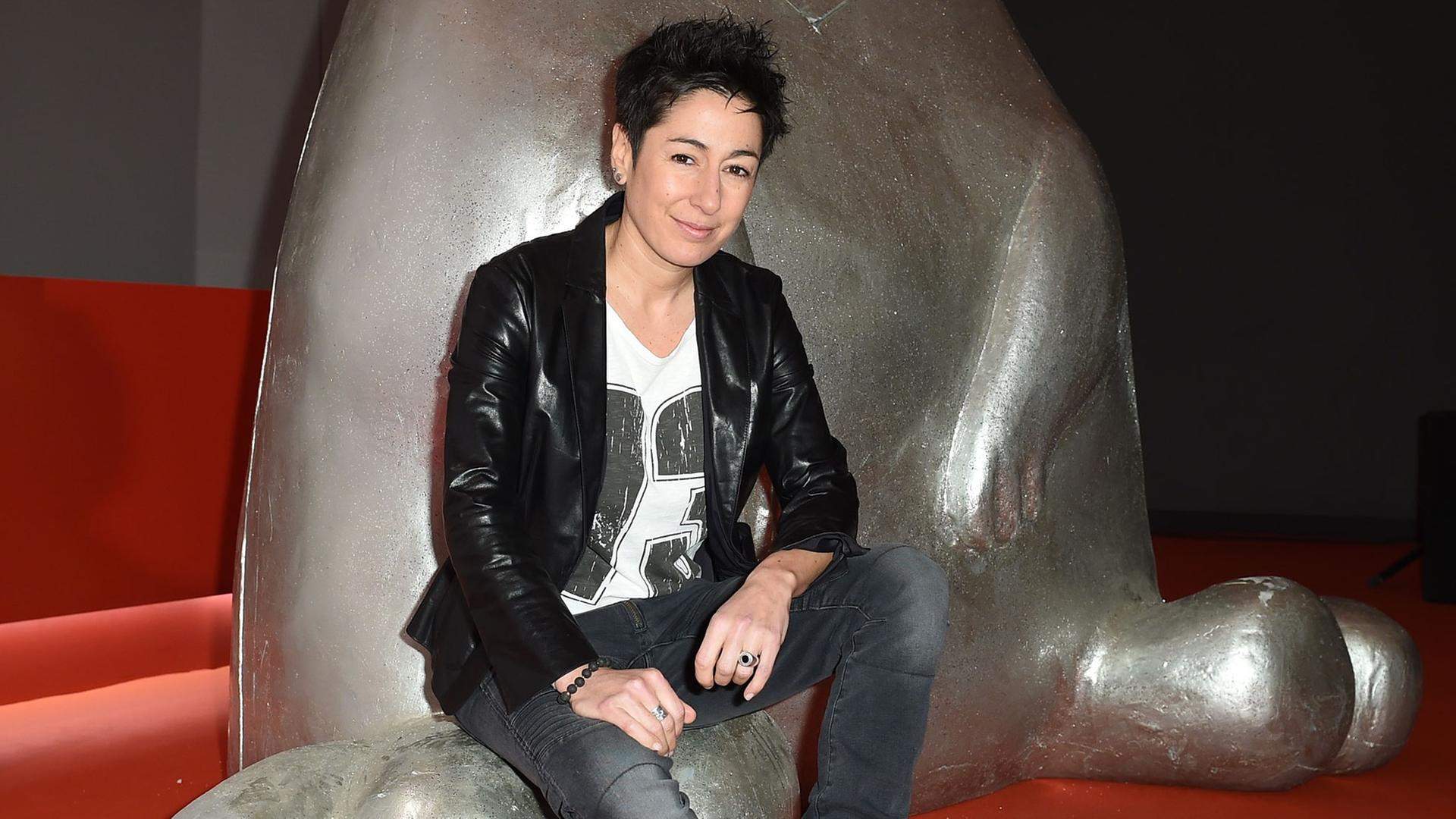 Die Moderatorin Dunja Hayali sitzt am 13.02.2015 in Berlin während der 65. Internationalen Filmfestspiele auf einer Skulptur.