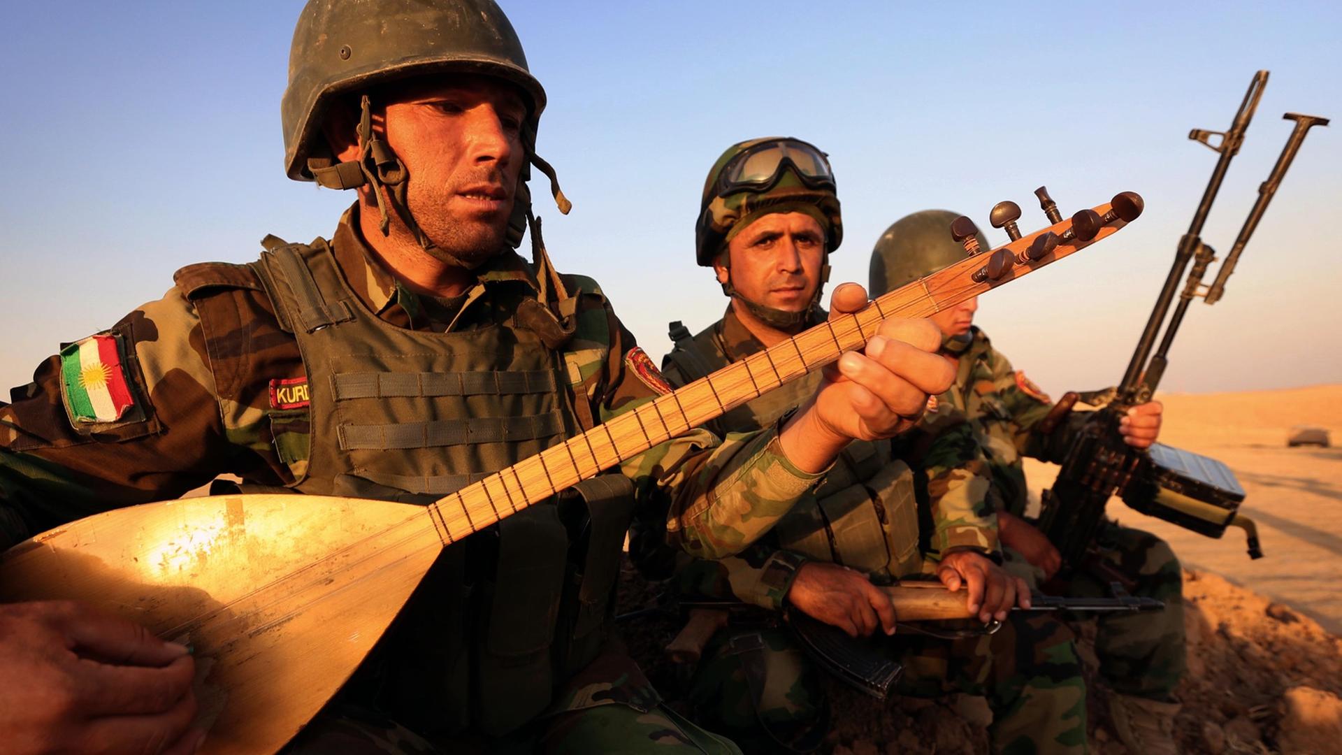 Ein irakisch-kurdischer Peshmerga-Kämpfer spielt auf einem Musikinstrument in der Nähe des Checkpoints Aski kalak, 40 km westlich von Arbil, des Haupstadt der Autonomen Kudischen Region Nordirak. Aufgenommen am 14. August 2014.