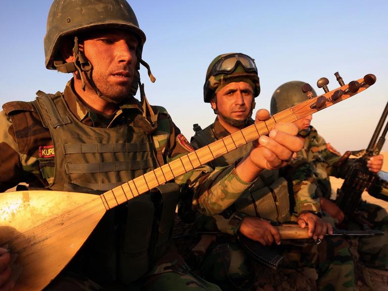 Ein irakisch-kurdischer Peshmerga-Kämpfer spielt auf einem Musikinstrument in der Nähe des Checkpoints Aski kalak, 40 km westlich von Arbil, des Haupstadt der Autonomen Kudischen Region Nordirak. Aufgenommen am 14. August 2014.