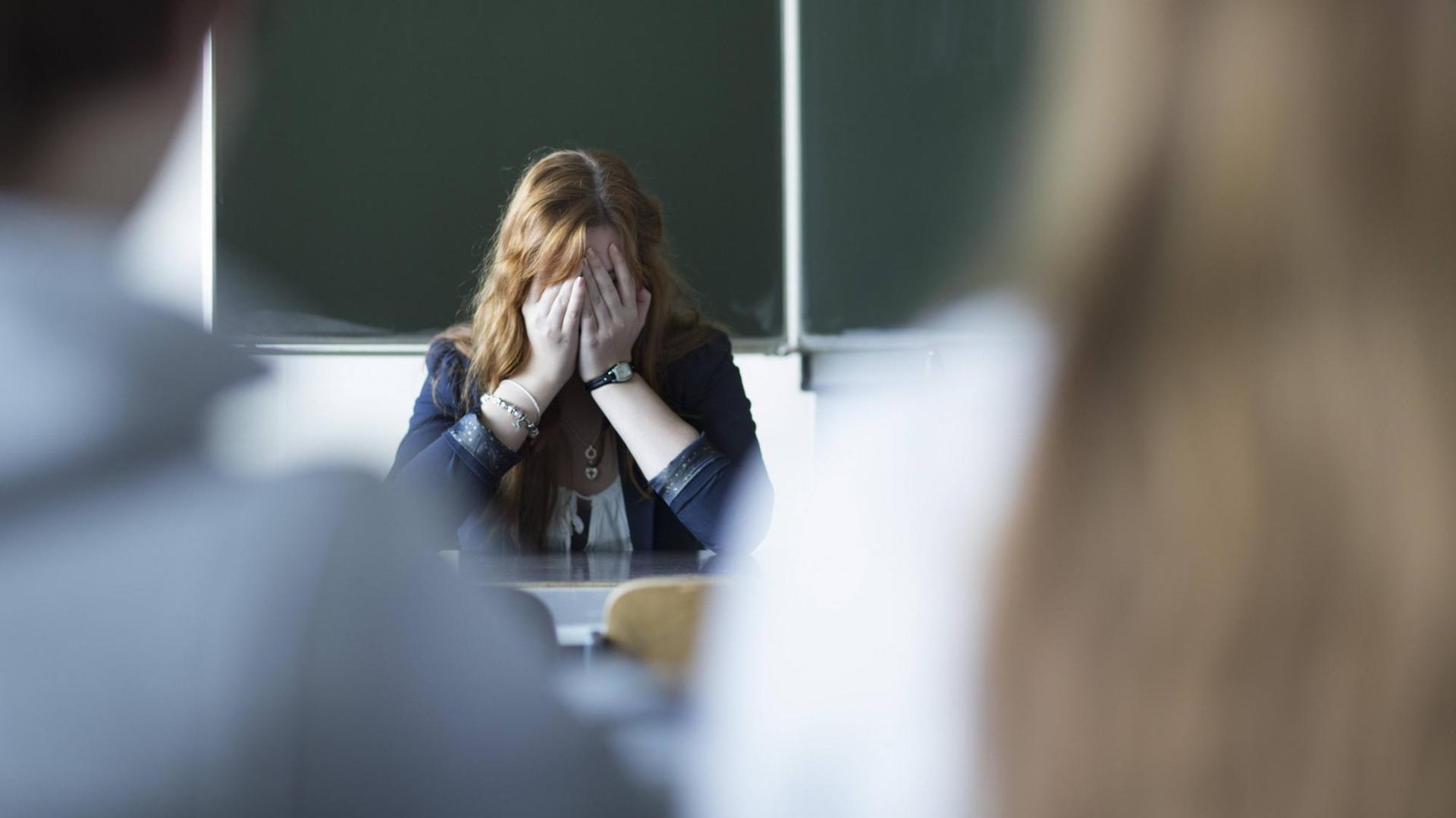 Das (gestellte) Foto zeigt eine verzweifelte Lehrerin im Klassenzimmer. Das (gestellte) Foto zeigt eine verzweifelte Lehrerin im Klassenzimmer.