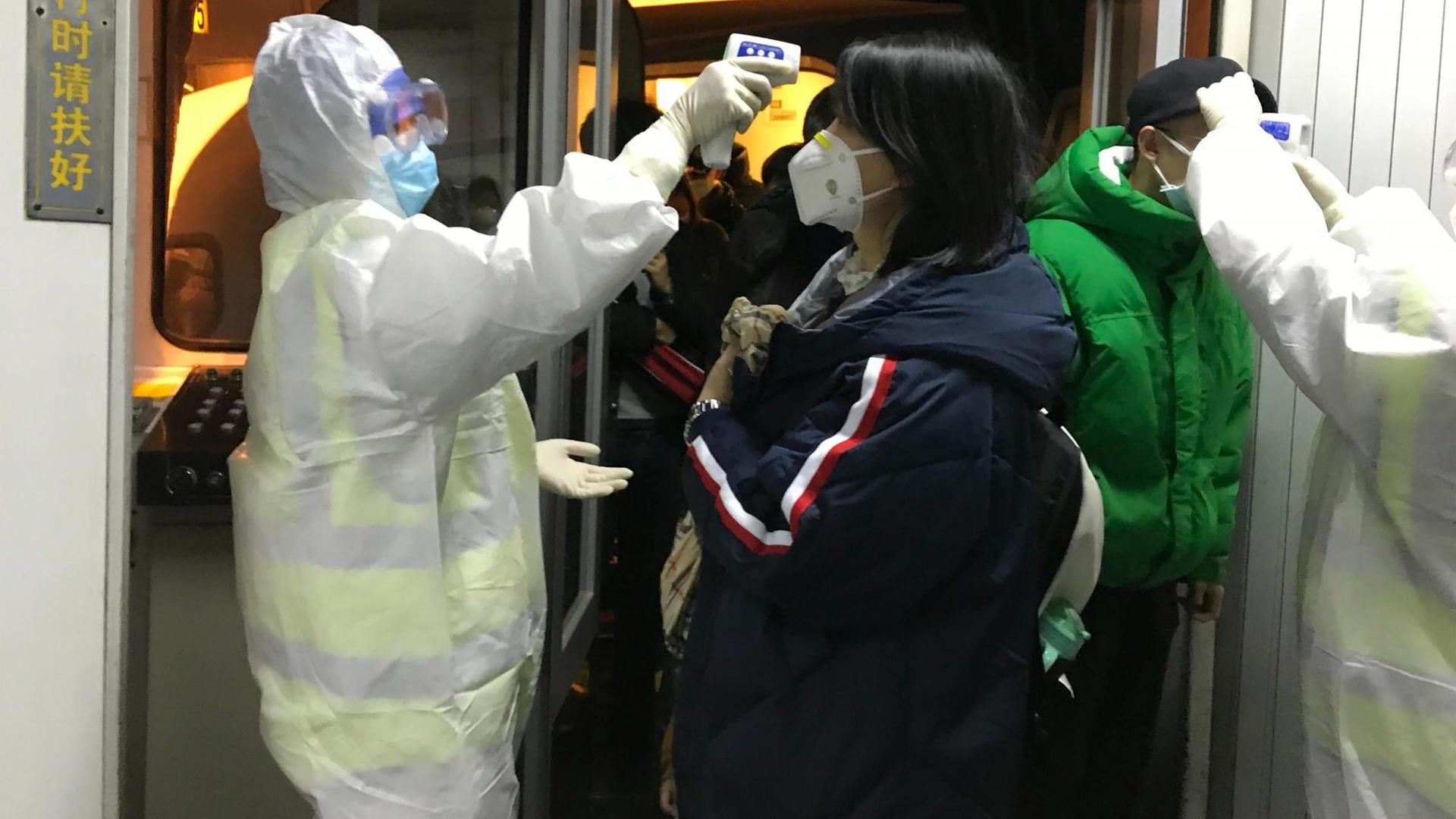 Das Bild zeigt chinesische Gesundheitsbeamte in Schutzanzügen. Sie kontrollieren am Flughafen von Peking die Körpertemperatur von Passagieren, die aus der Stadt Wuhan angereist sind. Das Bild zeigt chinesische Gesundheitsbeamte in Schutzanzügen. Sie kontrollieren am Flughafen von Peking die Körpertemperatur von Passagieren, die aus der Stadt Wuhan angereist sind.