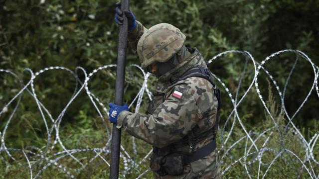 Ein polnischer Soldat errichtet einen Grenzzaun.