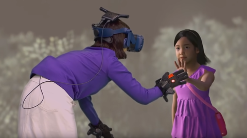 Eine Frau mit Virtual Reality-Brille und Handschuhen berührt die Hand eines jungen virtuellen Mädchens.