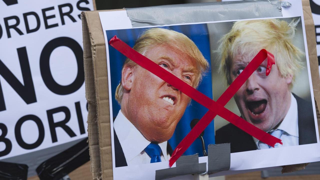 Ein Plakat mit Kariakturen von Donald Trump und Boris Johnson, die durchgestrichen sind. Andere Plakate zeigen die Aufschrit "No Borders". Ein Plakat mit Kariakturen von Donald Trump und Boris Johnson, die durchgestrichen sind. Andere Plakate zeigen die Aufschrit "No Borders".