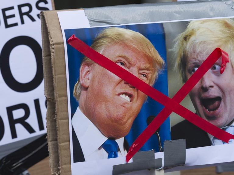 Ein Plakat mit Kariakturen von Donald Trump und Boris Johnson, die durchgestrichen sind. Andere Plakate zeigen die Aufschrit "No Borders".