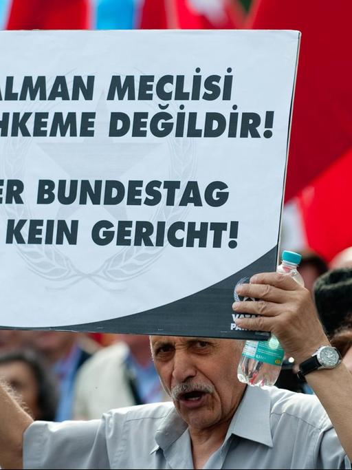 Teilnehmer der Demonstration halten ein Schild hoch mit dem Slogan "Der Bundestag ist kein Gericht".