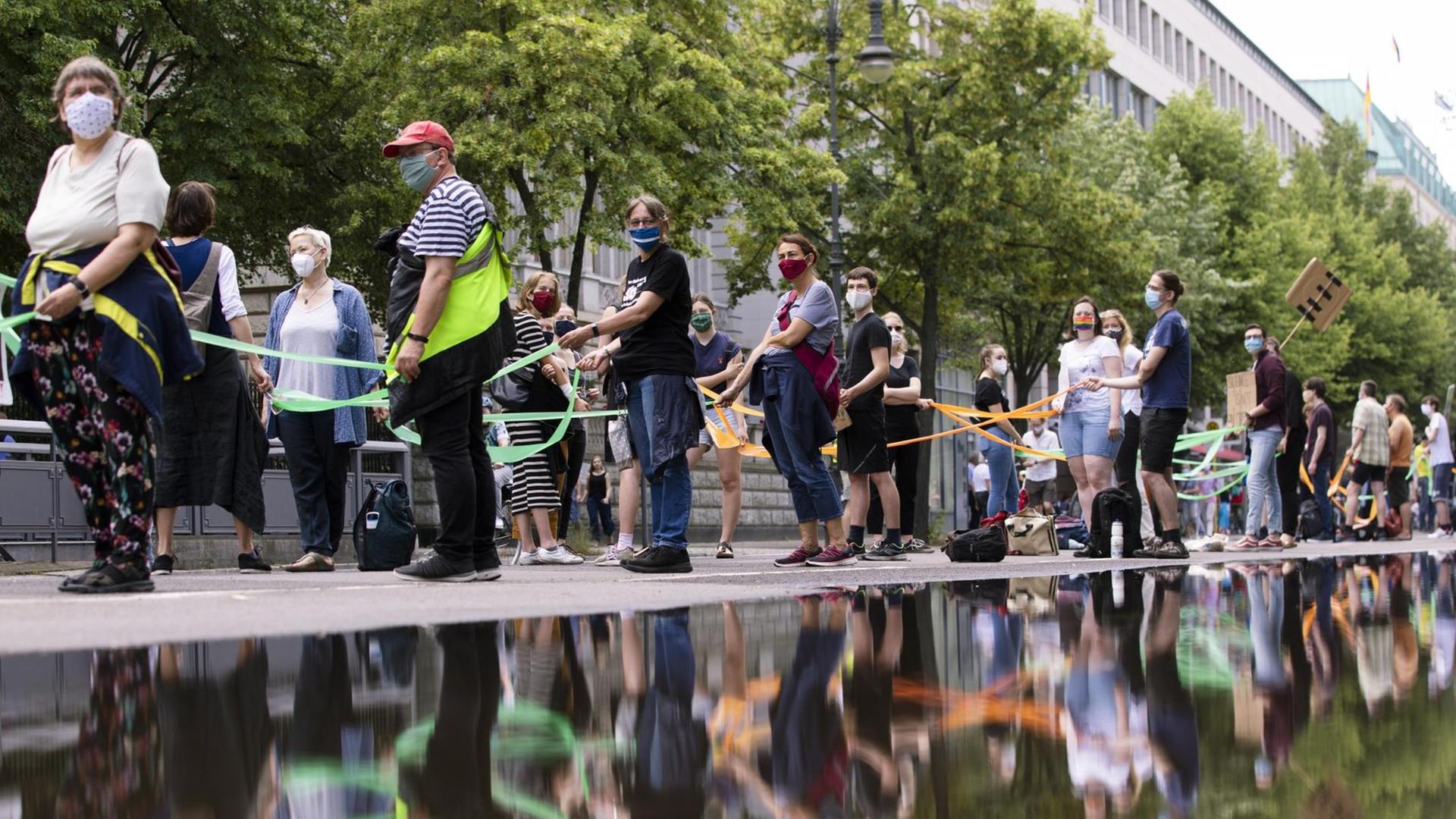Demonstranten bilden eine menschliche Kette vom Brandenburger Tor zum Hermannplatz, indem sie soziale Distanz wahren, um am 14. Juni 2020 in Berlin gegen soziale Ungerechtigkeit und Rassismus zu protestieren. Demonstranten bilden eine menschliche Kette vom Brandenburger Tor zum Hermannplatz, indem sie soziale Distanz wahren, um am 14. Juni 2020 in Berlin gegen soziale Ungerechtigkeit und Rassismus zu protestieren.