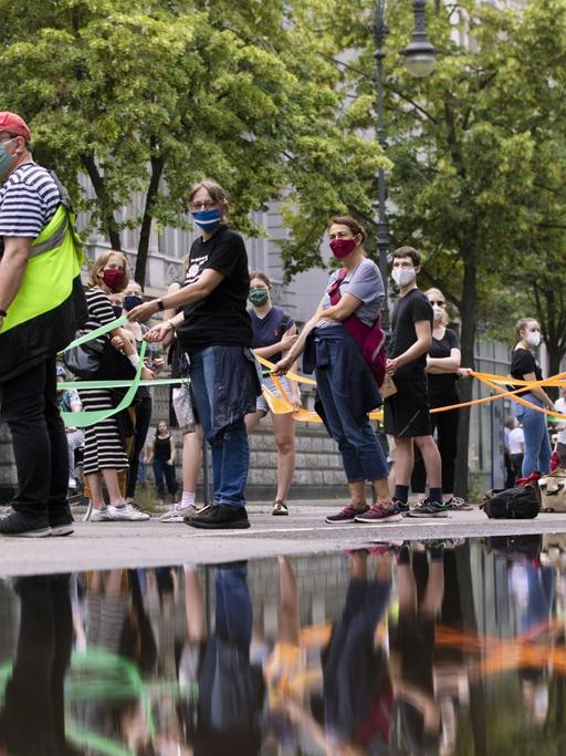 Demonstranten bilden eine menschliche Kette vom Brandenburger Tor zum Hermannplatz, indem sie soziale Distanz wahren, um am 14. Juni 2020 in Berlin gegen soziale Ungerechtigkeit und Rassismus zu protestieren.
