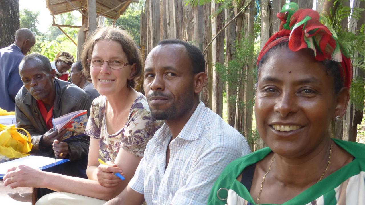 Christel Ahrens sitzt in Äthiopien zwischen Menschen und grinst in die Kamera.