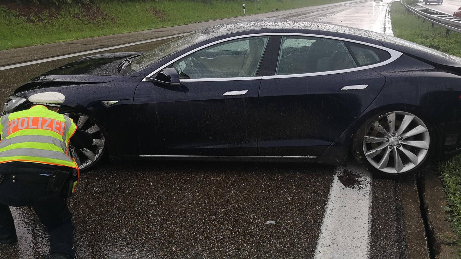 Ein Auto steht quer auf der Fahrbahn einer Autobahn. Vor dem rechten Vorderrad kniet ein Polizist. Ein Auto steht quer auf der Fahrbahn einer Autobahn. Vor dem rechten Vorderrad kniet ein Polizist.
