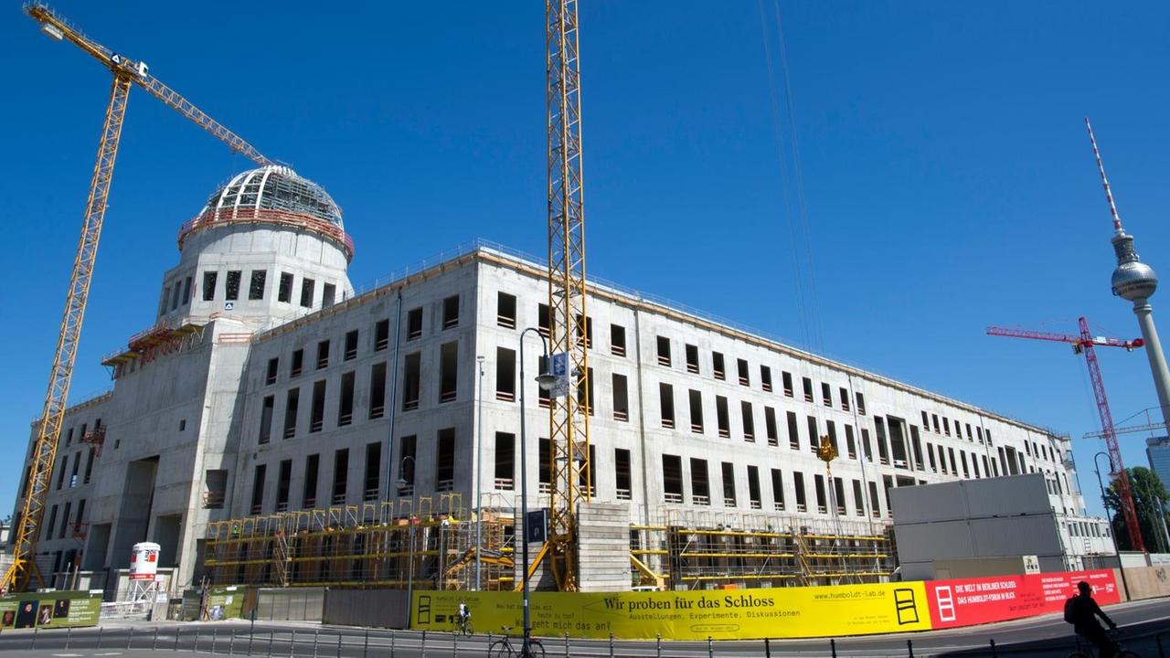 Baukräne ragen an der Baustelle des neuen Berliner Stadtschlosses in den blauen Himmel.