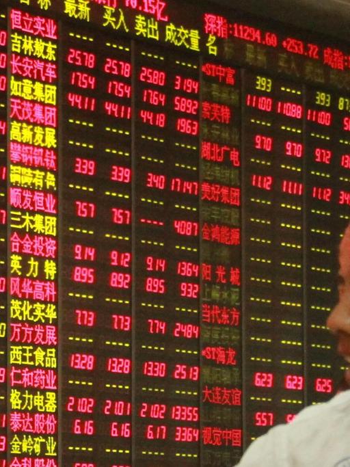 Ein Mann betrachtet eine Anzeigetafel mit chinesischen Börsenkursen