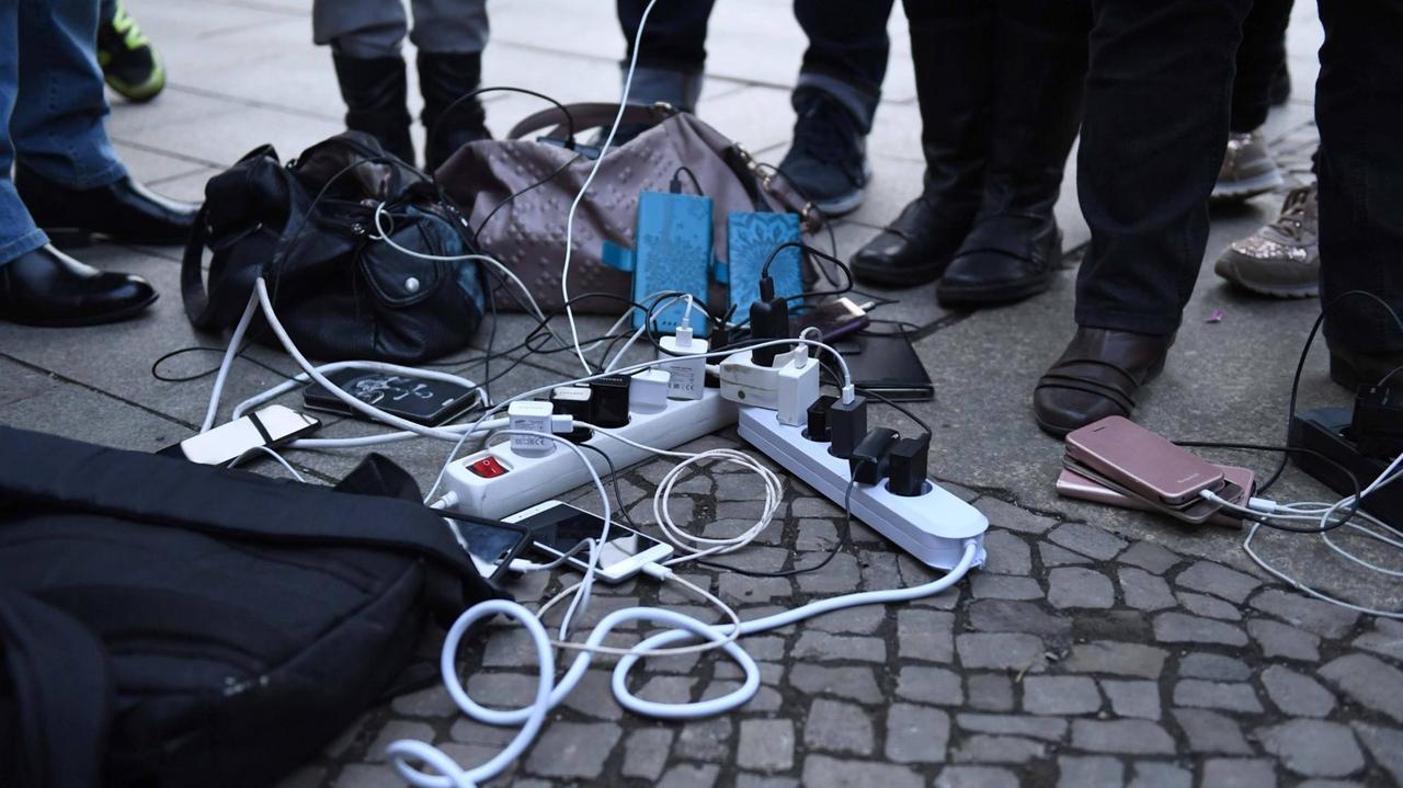 Menschen warten am Rathaus Köpenick am Katastrophenschutzwagen des ASB, bis ihre Mobiltelefone aufgeladen sind. Zu sehen sind Mehrfachstecker mit Smartphones. Menschen warten am Rathaus Köpenick am Katastrophenschutzwagen des ASB, bis ihre Mobiltelefone aufgeladen sind. Zu sehen sind Mehrfachstecker mit Smartphones.