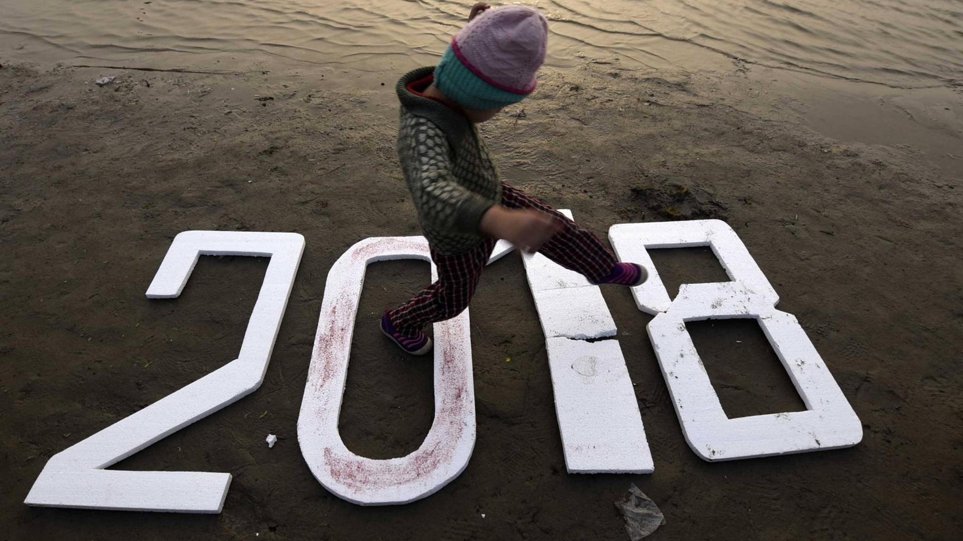 Ein Kind läuft an einem Strand in Indien über die Zahlen 2018. Ein Kind läuft an einem Strand in Indien über die Zahlen 2018.