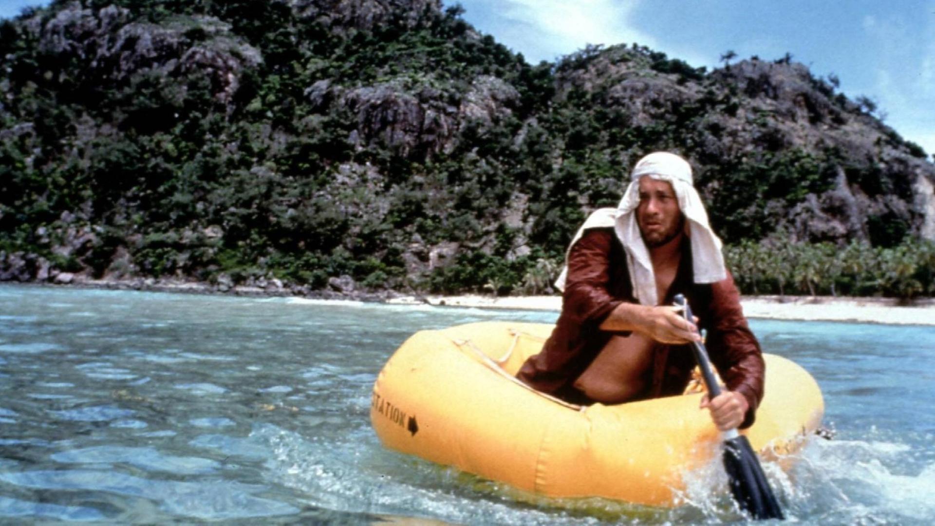 Filmstill aus dem Kinofilm Cast Away mit Tom Hanks. Das Bild zeigt einen ausgemärgelten Mann mit Turban in einem Schlauboot vor einer einsamen Insel. Filmstill aus dem Kinofilm Cast Away mit Tom Hanks. Das Bild zeigt einen ausgemärgelten Mann mit Turban in einem Schlauboot vor einer einsamen Insel.