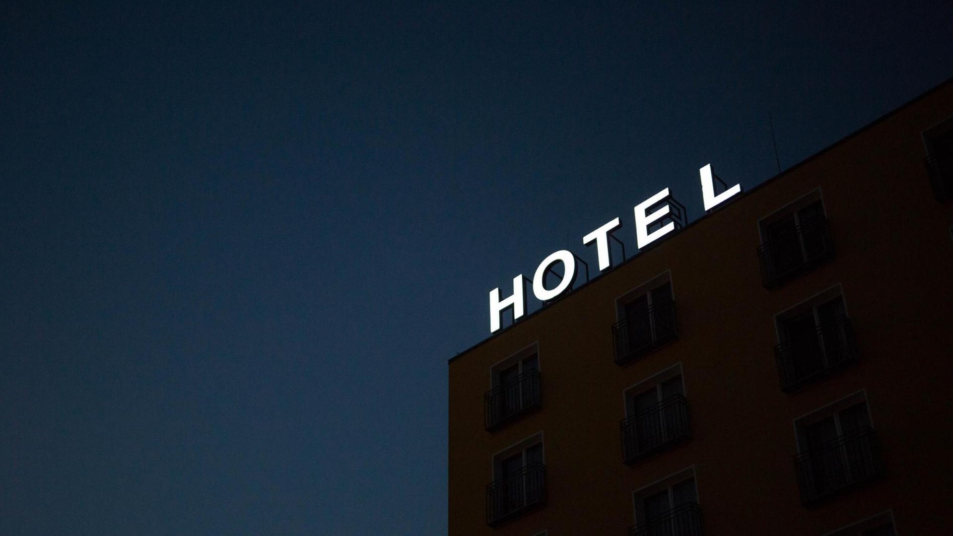 Auf dem Dach eines Gebäudes leuchtet der Schriftzug "HOTEL" vor dem Nachthimmel. Auf dem Dach eines Gebäudes leuchtet der Schriftzug "HOTEL" vor dem Nachthimmel.