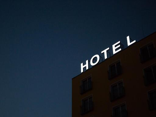 Auf dem Dach eines Gebäudes leuchtet der Schriftzug "HOTEL" vor dem Nachthimmel.