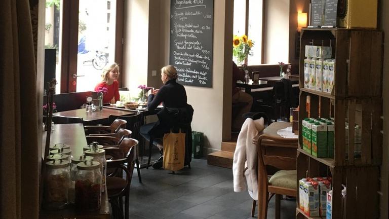Zwei Frauen sitzen sich an einem gedeckten Cafétisch gegenüber. Zwei Frauen sitzen sich an einem gedeckten Cafétisch gegenüber.