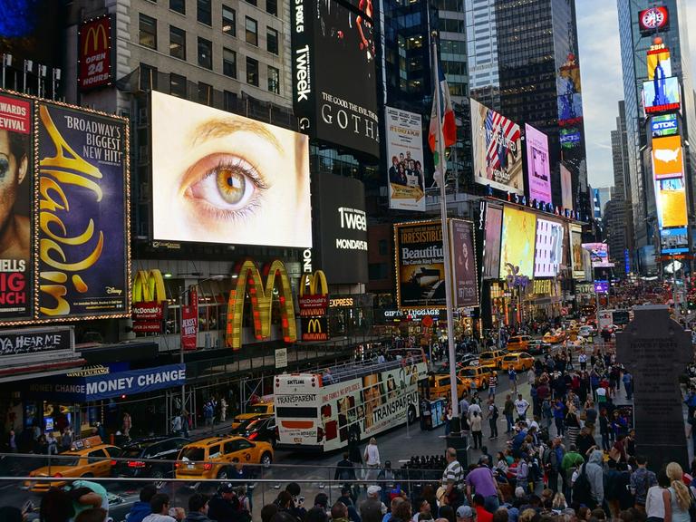 Der Times Square in New York mit zahllosen Reklametafeln an Häuserwänden und auf Fahrzeugen.