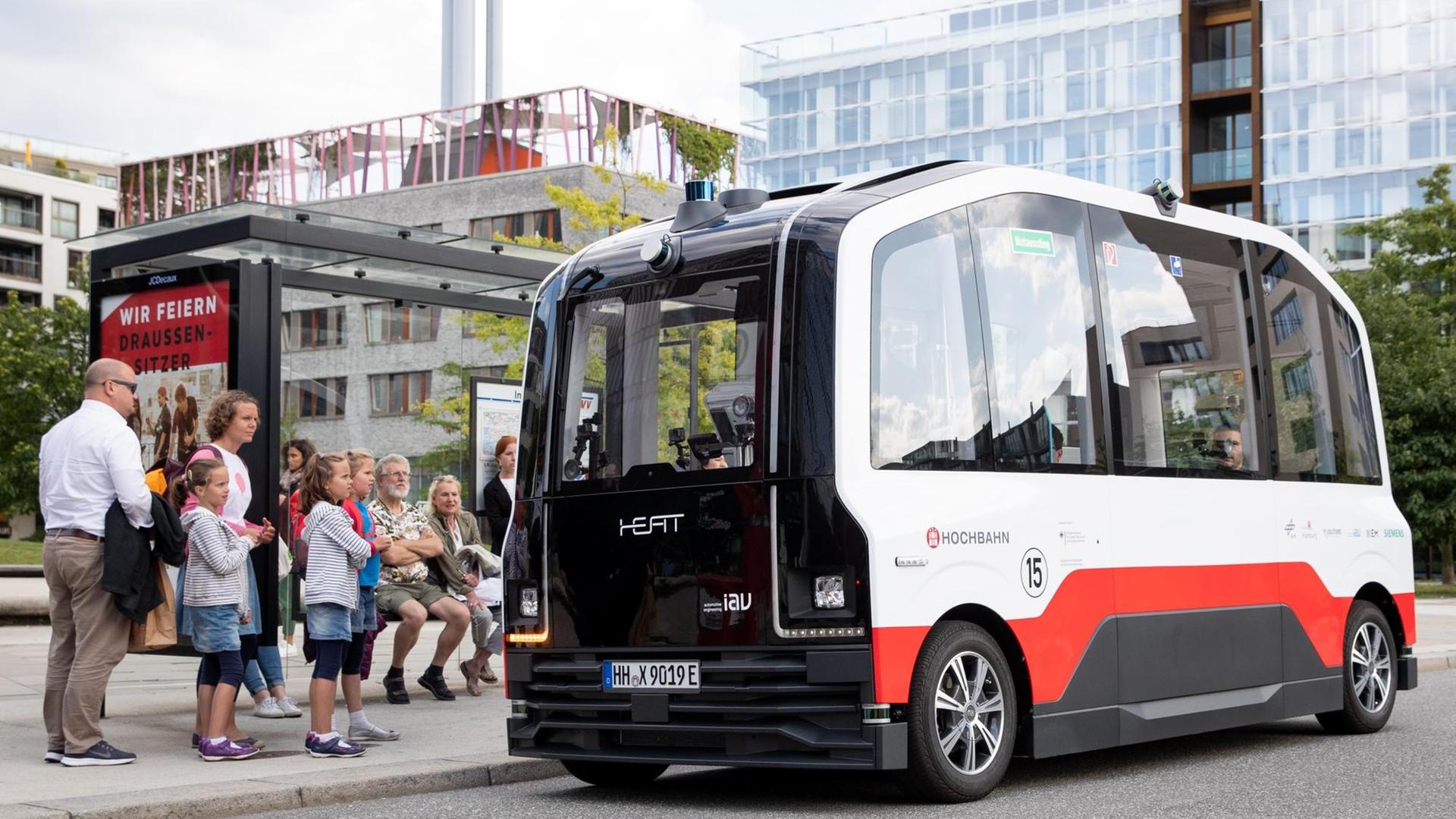 Derautonom fahrende Kleinbus HEAT ist bei einer ersten Testfahrt in der Hafencity unterwegs und hält an einer Bushaltestelle.