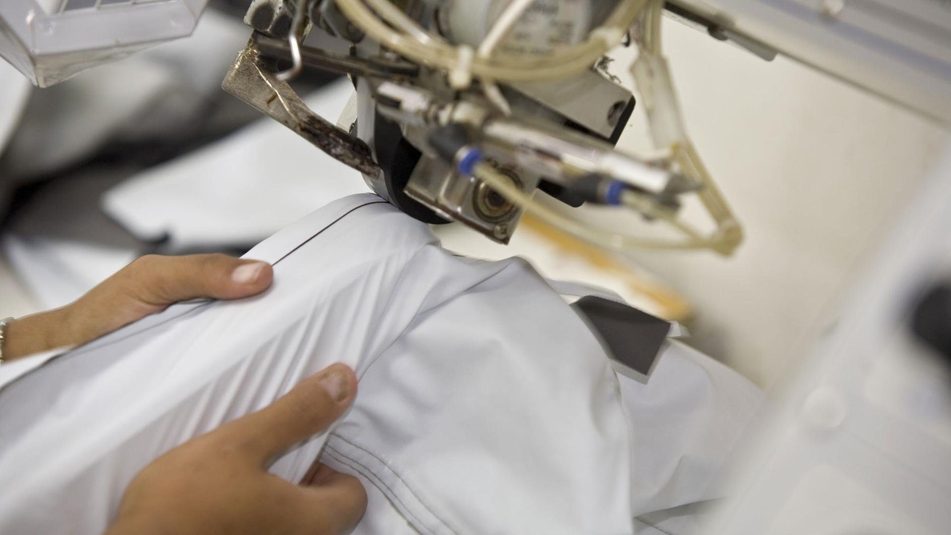 Eine Näherin arbeitet an einer Maschine, mit der Nähte mit einem Spezialband wasserdicht versiegelt werden. Eine Näherin arbeitet an einer Maschine, mit der Nähte mit einem Spezialband wasserdicht versiegelt werden.