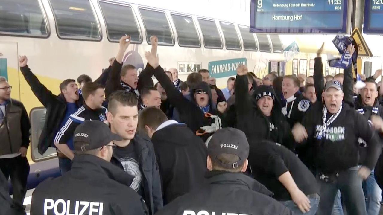 HSV-Fans gehen auf einem Bahnsteig in Bremen Richtung Ausgang des Bahnhofs, nachdem sie mit dem Zug aus Hamburg ankamen und werden dabei von Polizisten beobachtet. HSV-Fans gehen auf einem Bahnsteig in Bremen Richtung Ausgang des Bahnhofs, nachdem sie mit dem Zug aus Hamburg ankamen und werden dabei von Polizisten beobachtet.