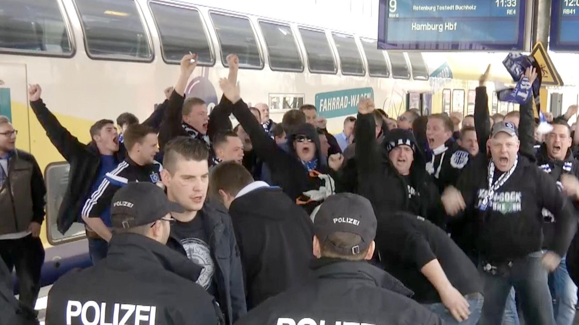 HSV-Fans gehen auf einem Bahnsteig in Bremen Richtung Ausgang des Bahnhofs, nachdem sie mit dem Zug aus Hamburg ankamen und werden dabei von Polizisten beobachtet. HSV-Fans gehen auf einem Bahnsteig in Bremen Richtung Ausgang des Bahnhofs, nachdem sie mit dem Zug aus Hamburg ankamen und werden dabei von Polizisten beobachtet.