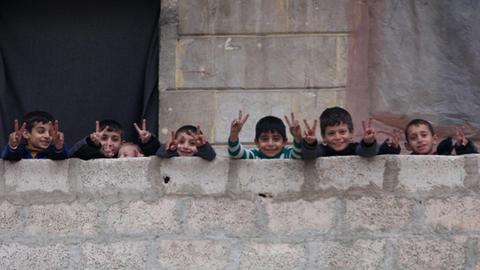 Kinder in Ost-Aleppo machen das Friedenszeichen auf einem Balkon