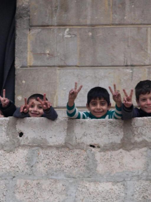 Kinder in Ost-Aleppo machen das Friedenszeichen auf einem Balkon