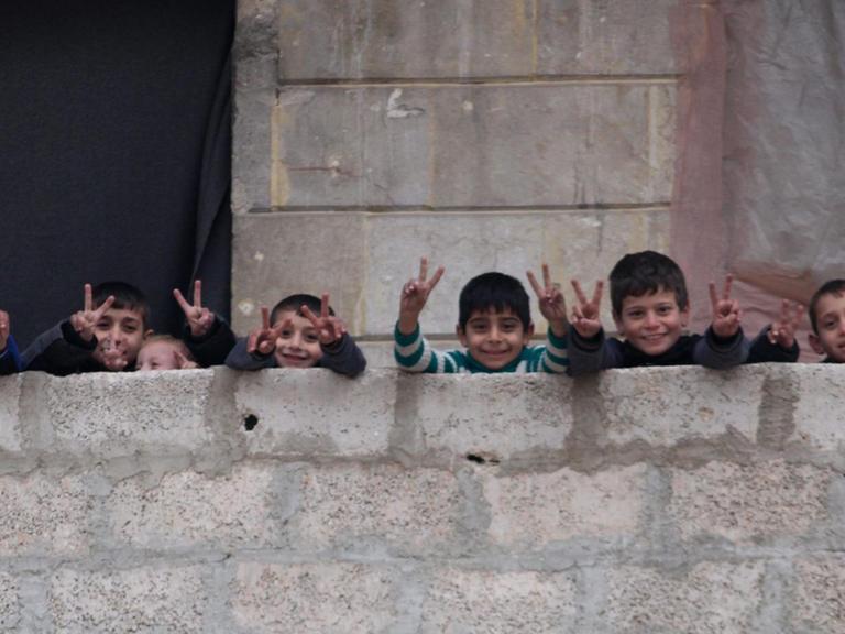 Kinder in Ost-Aleppo machen das Friedenszeichen auf einem Balkon