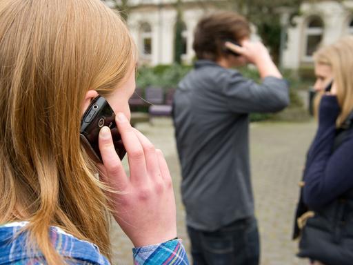 Zehntklässler telefonieren am 22.04.2013 auf einem Schulhof in Braunschweig (Niedersachsen), nachdem sie für eine Woche freiwillig auf ihr Handy verzichtet hatten.