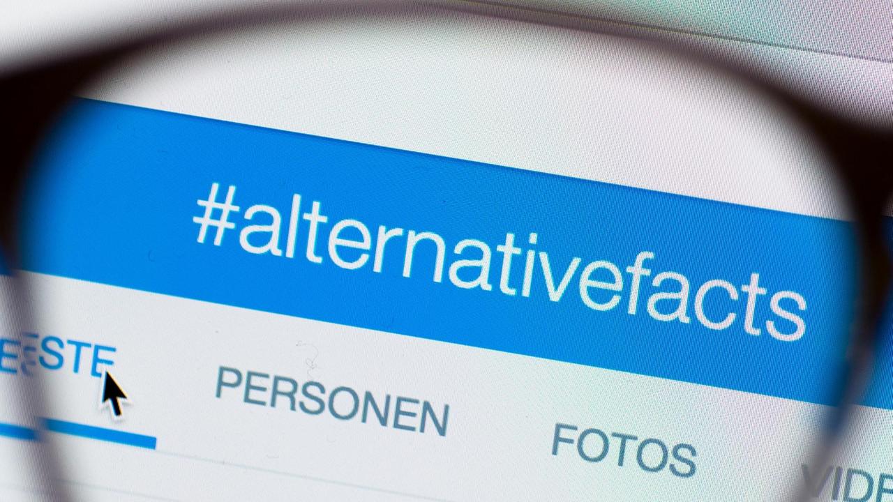Für eine Illustration wird ein Teil einer Brille vor einen Computerbildschirm gehalten, auf dem auf Twitter ein Hashtag #alternativefacts (alternative Fakten) zu sehen ist.