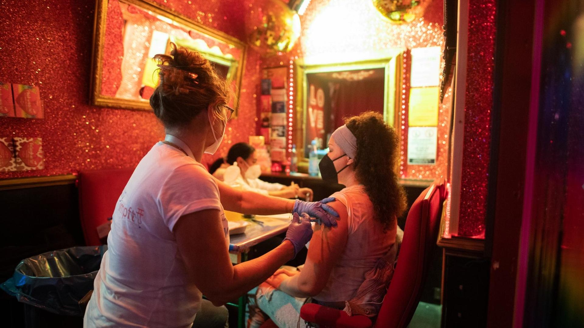 Eine junge Frau lässt sich im Rahmen der Aktion «Kiez-Piks» in der Bar «Wunderbar» nahe der Reeperbahn im Stadtteil St. Pauli gegen das Coronavirus impfen. Nach erfolgter Impfung erhalten die Impflinge einen Pizza-Gutschein. Eine junge Frau lässt sich im Rahmen der Aktion «Kiez-Piks» in der Bar «Wunderbar» nahe der Reeperbahn im Stadtteil St. Pauli gegen das Coronavirus impfen. Nach erfolgter Impfung erhalten die Impflinge einen Pizza-Gutschein.