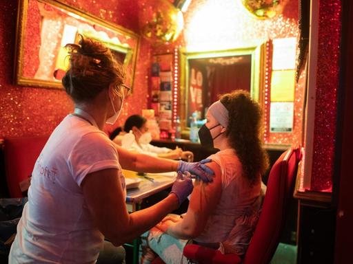 Eine junge Frau lässt sich im Rahmen der Aktion «Kiez-Piks» in der Bar «Wunderbar» nahe der Reeperbahn im Stadtteil St. Pauli gegen das Coronavirus impfen. Nach erfolgter Impfung erhalten die Impflinge einen Pizza-Gutschein.