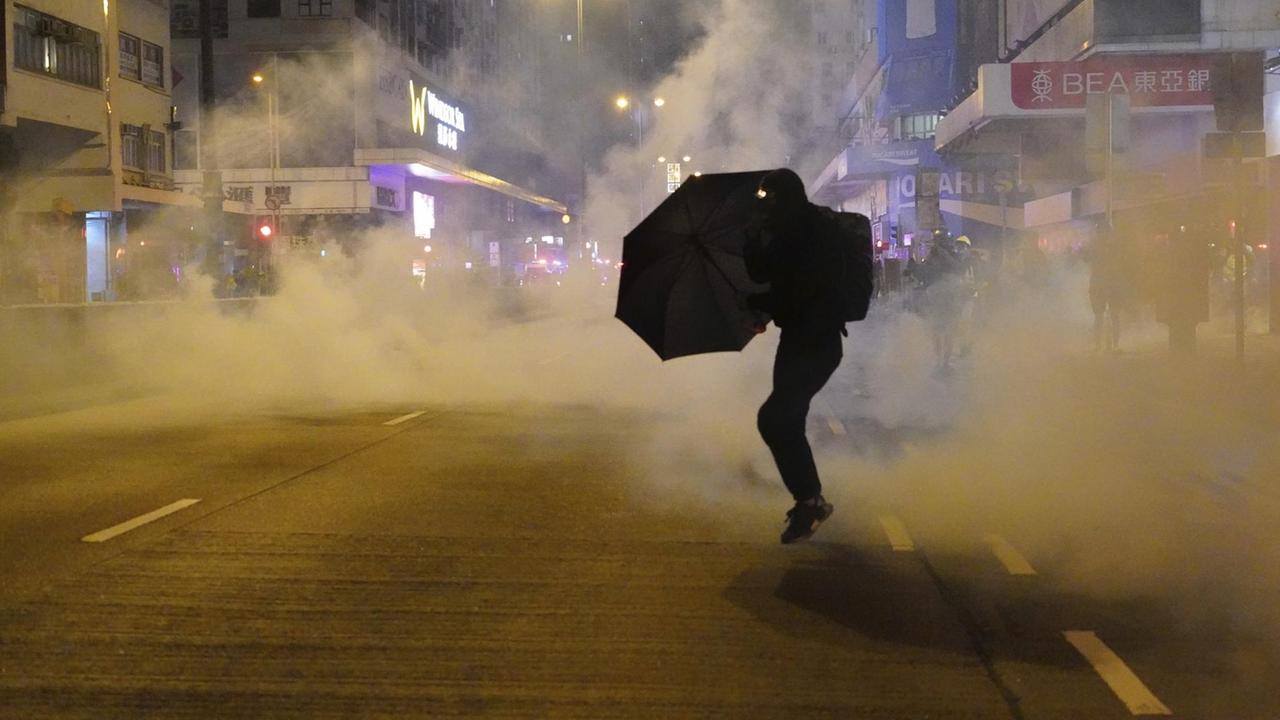 Ein regierungskritischer Demonstrant schützt sich mit einem Regenschirm vor Tränengas. Ein regierungskritischer Demonstrant schützt sich mit einem Regenschirm vor Tränengas.